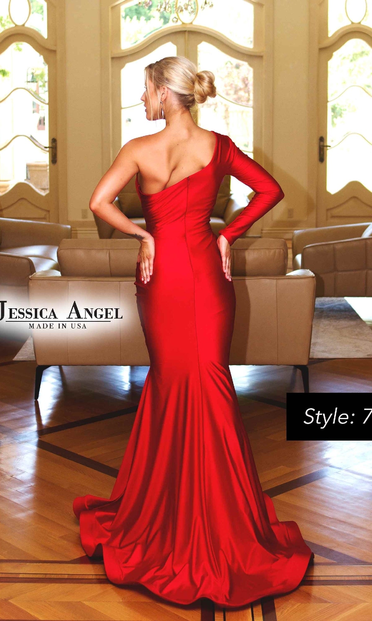 A woman wearing the fitted, floor-length Jessica Angel 711 One-Sleeve Long Prom Dress stands with her back to the camera in a bright room featuring large windows and beige furniture.